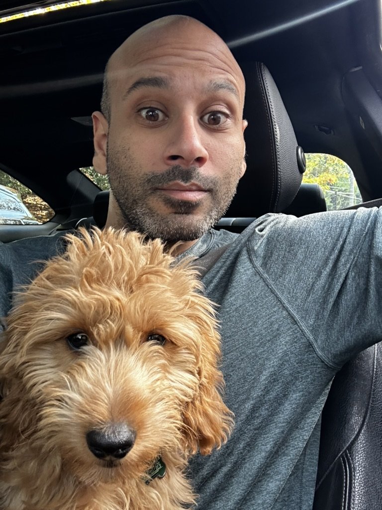 Malek Damiri in the driver's seat with Ben the goldendoodle in front of him