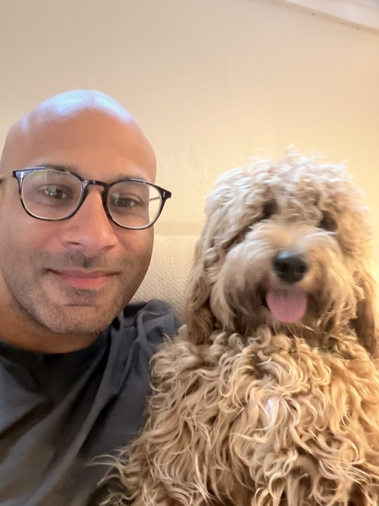 Malek Damiri in glasses taking a selfie with Ben, his goldendoodle