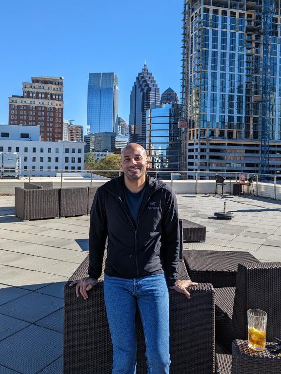 Malek Damiri on a rooftop terrace with the Midtown Atlanta skyline behind him