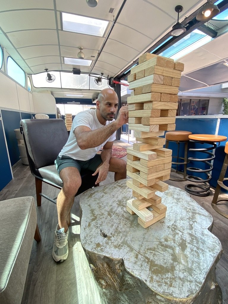 Malek Damiri concentrating on a tall tower of giant Jenga blocks