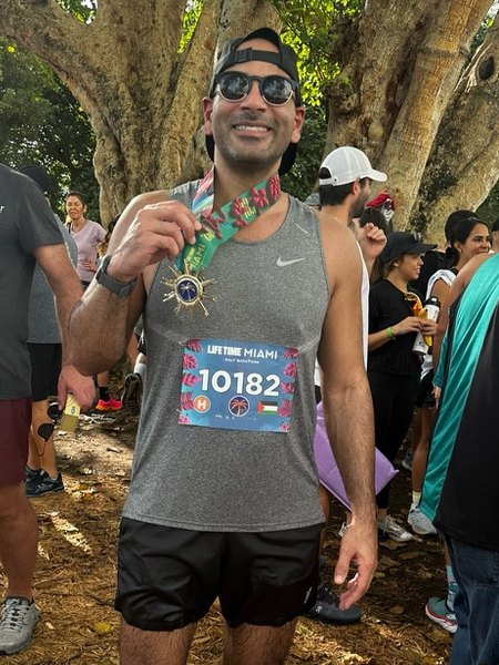 Malek Damiri holding a finisher's medal after the Miami Half Marathon